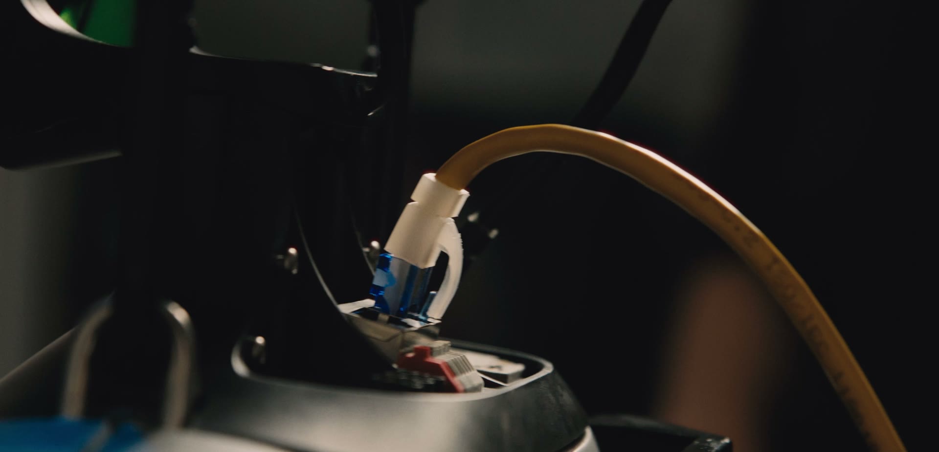 Close-up of an orange data cable plugged into a robot.